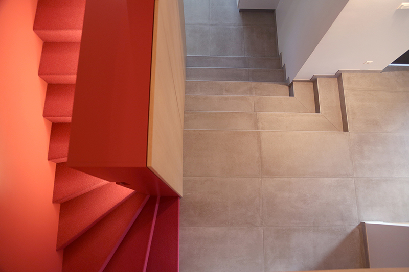 Agencement sur mesure par LDC Agencement – L’Arche du Bois : escalier rouge à gauche, escalier blanc à droite, séparés par un mur.