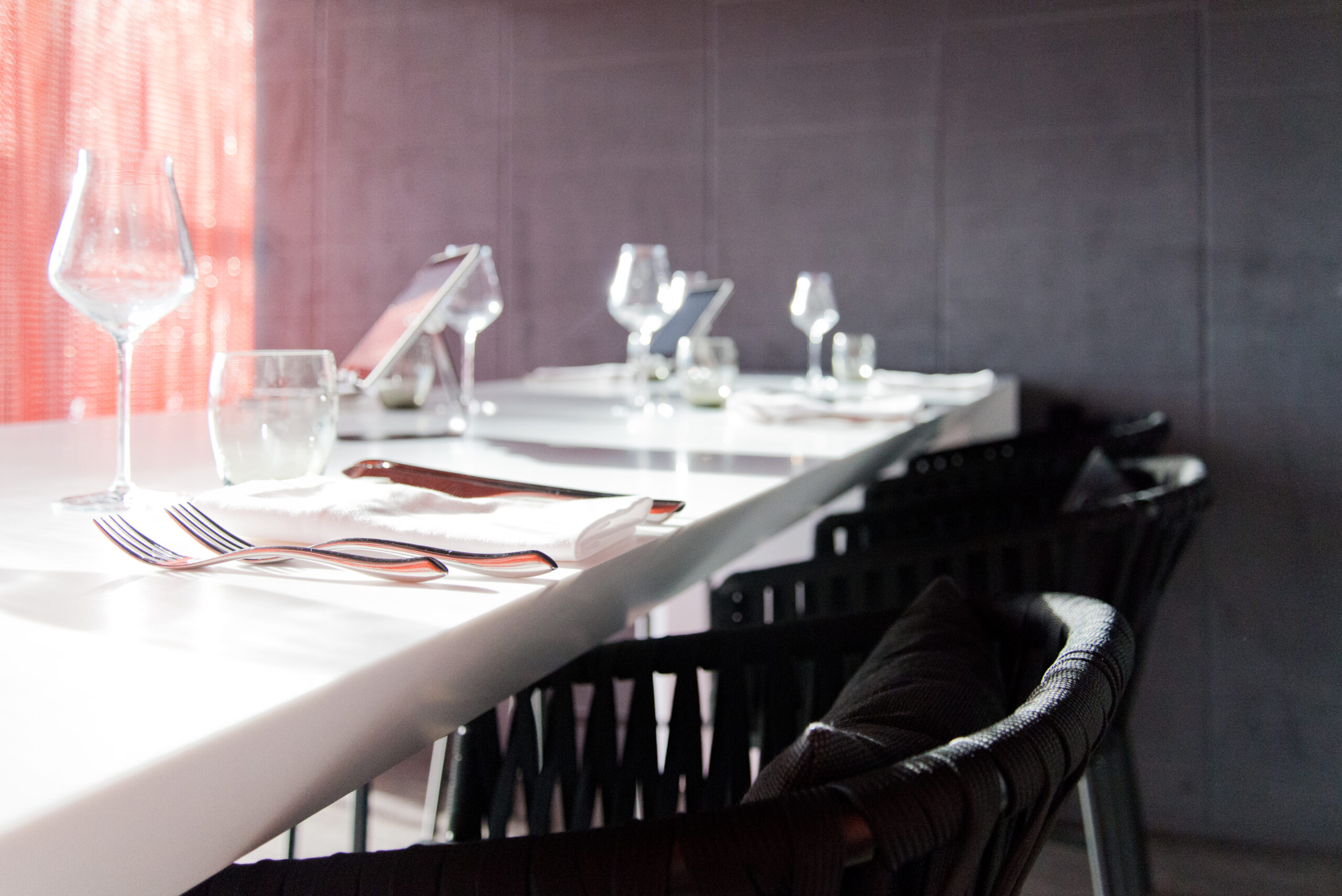 Vue rapprochée de tables et chaises de salle à manger, avec des verres soigneusement disposés sur les plateaux — un agencement raffiné et accueillant signé Arche du Bois, parfait pour un espace de restauration convivial et soigné