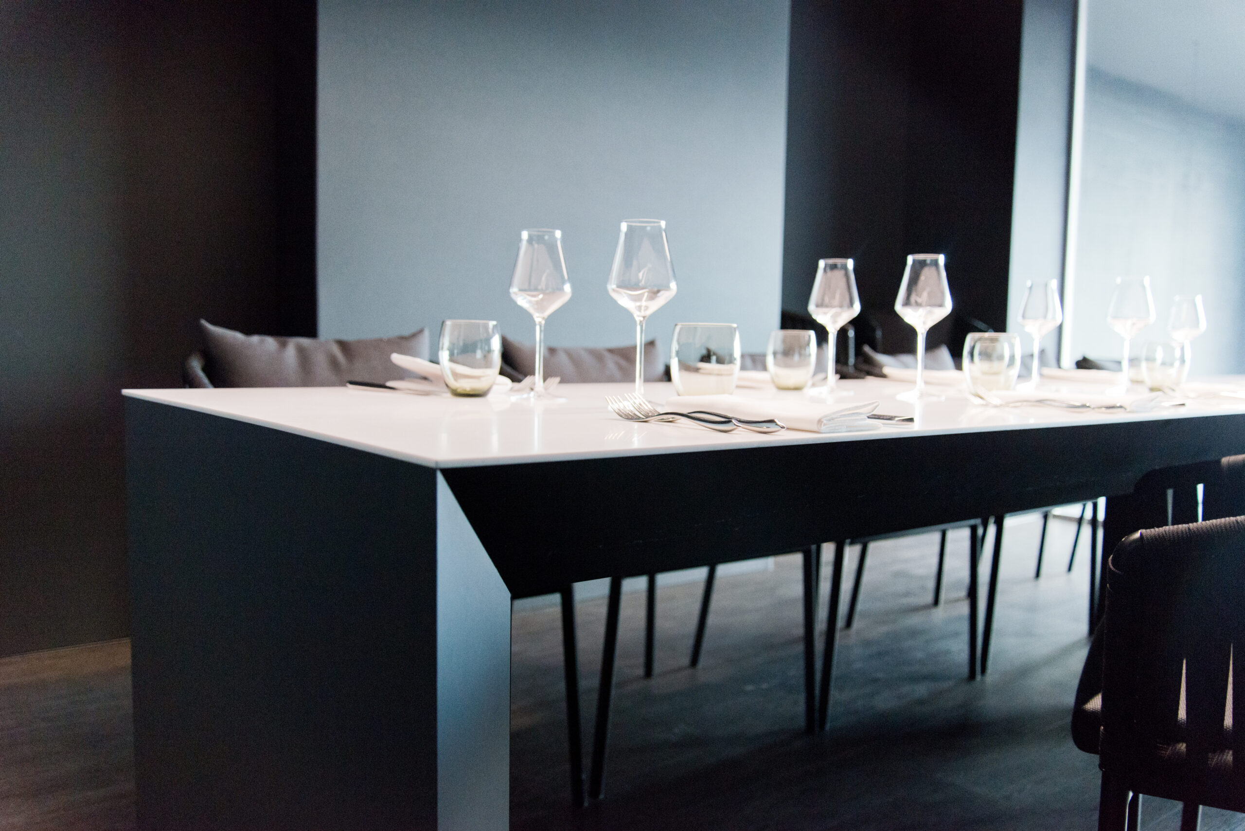 Grande table en bois entourée de chaises confortables, avec plusieurs verres posés sur le plateau