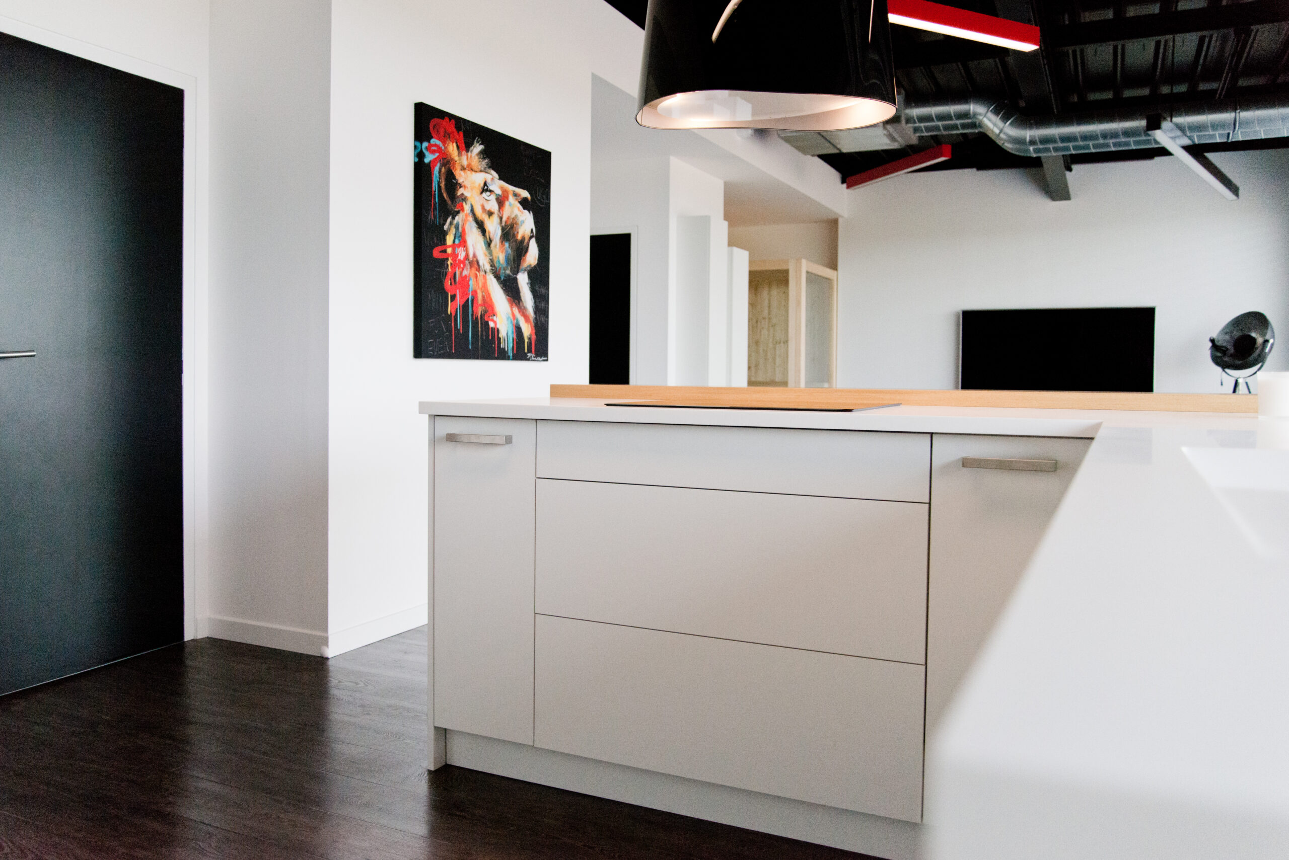 Espace intérieur avec meuble et table blancs, une porte noire sur la gauche de l’image, et un cadre photo accroché au mur adjacent — un agencement minimaliste et contrasté signé Arche du Bois, combinant lignes épurées et touches graphiques.