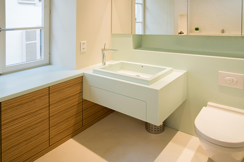 Salle de bain sur mesure par LDC Agencement – L’Arche du Bois : vasque avec robinet moderne, toilette à droite, placards bas à gauche et placards hauts avec fenêtre, design contemporain et agencement personnalisé.