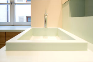 Salle de bain sur mesure par LDC Agencement – L’Arche du Bois : vasque avec robinet et fenêtre en arrière-plan, design moderne et agencement personnalisé