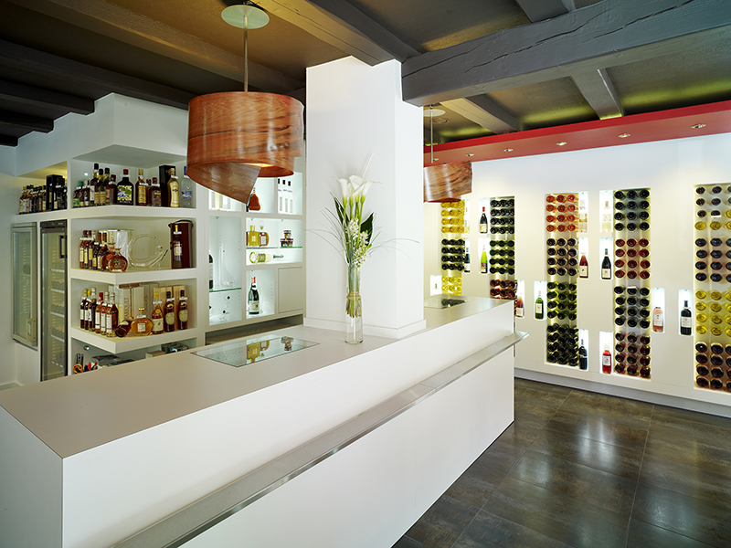 Étagères en bois accueillant des bouteilles d’alcool soigneusement disposées, dans un agencement élégant et structuré réalisé par Arche du Bois pour une présentation raffinée des spiritueux.