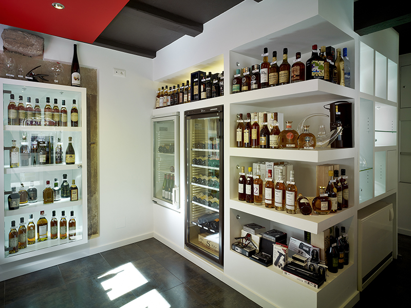 Étagères en bois accueillant des bouteilles d’alcool soigneusement disposées, dans un agencement élégant et structuré réalisé par Arche du Bois pour une présentation raffinée des spiritueux.