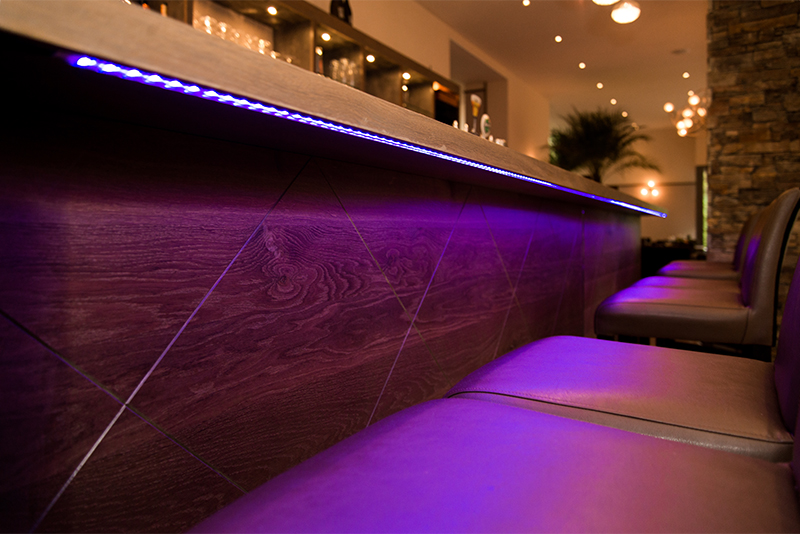 Éclairage LED intégré sous le comptoir de bar, créant une ambiance lumineuse moderne et élégante