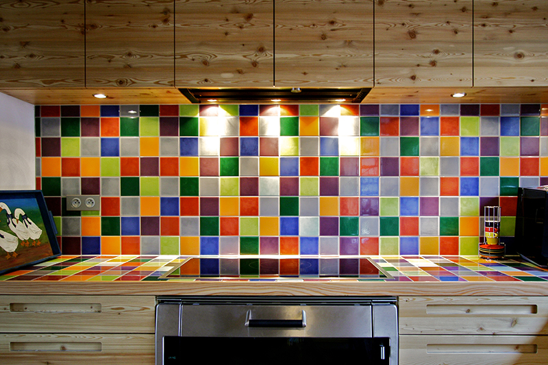 Agencement de cuisine sur mesure par LDC Agencement – L’Arche du Bois : série de placards hauts et bas, plan de travail et crédence habillés de carreaux colorés
