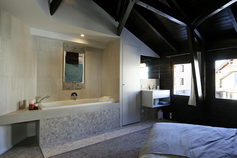 Salle de bain avec une baignoire à gauche et un plan vasque à droite, dans un agencement épuré et fonctionnel.