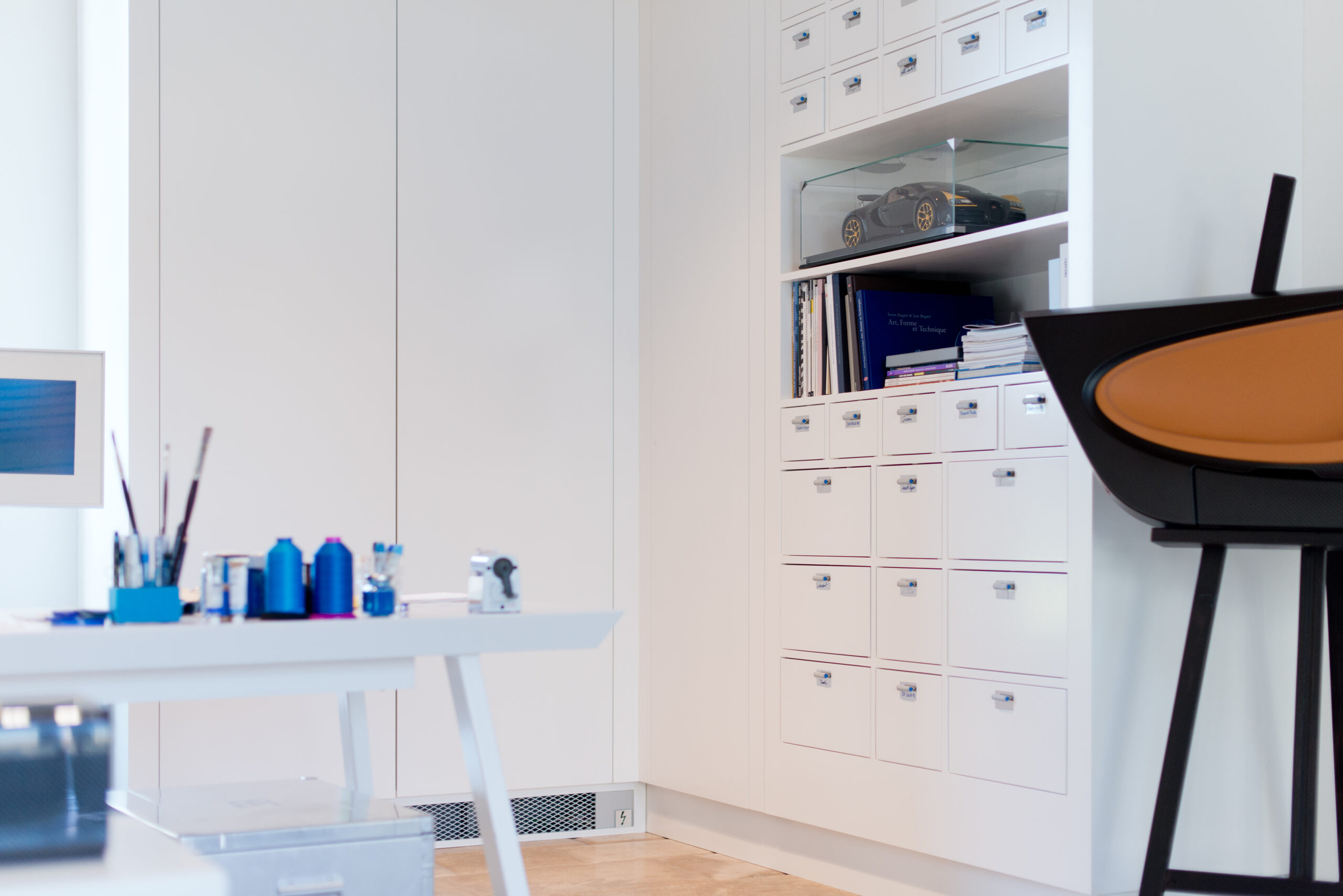 Armoire blanche accompagnée d’un ensemble de tiroirs intégrés, avec une table visible sur la gauche de l’image