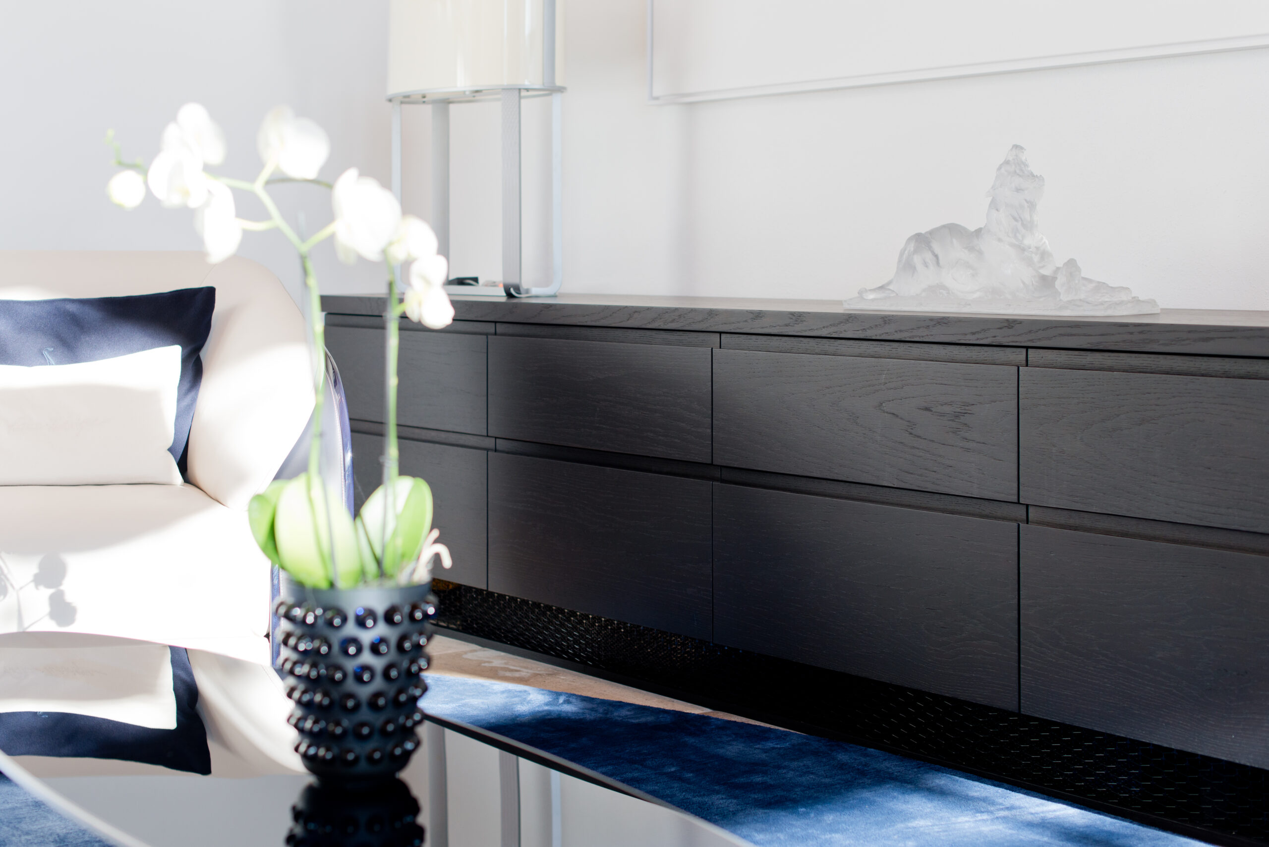 Vase décoratif posé sur une table, avec en arrière-plan une armoire noire