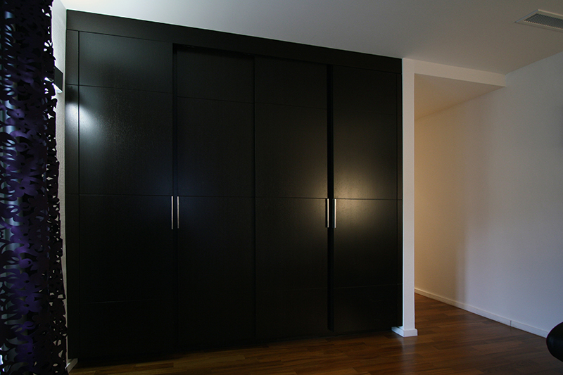 Placards équipés de portes en bois noir, conçus sur mesure par Arche du Bois — un agencement raffiné et moderne alliant esthétisme sombre et fonctionnalité discrète.