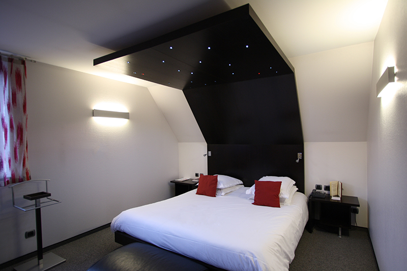 Lit double avec une grande tête de lit en bois s’étendant jusqu’au plafond, intégrant un éclairage LED discret en partie haute — un aménagement raffiné et sur mesure réalisé par Arche du Bois pour une chambre contemporaine et chaleureuse.