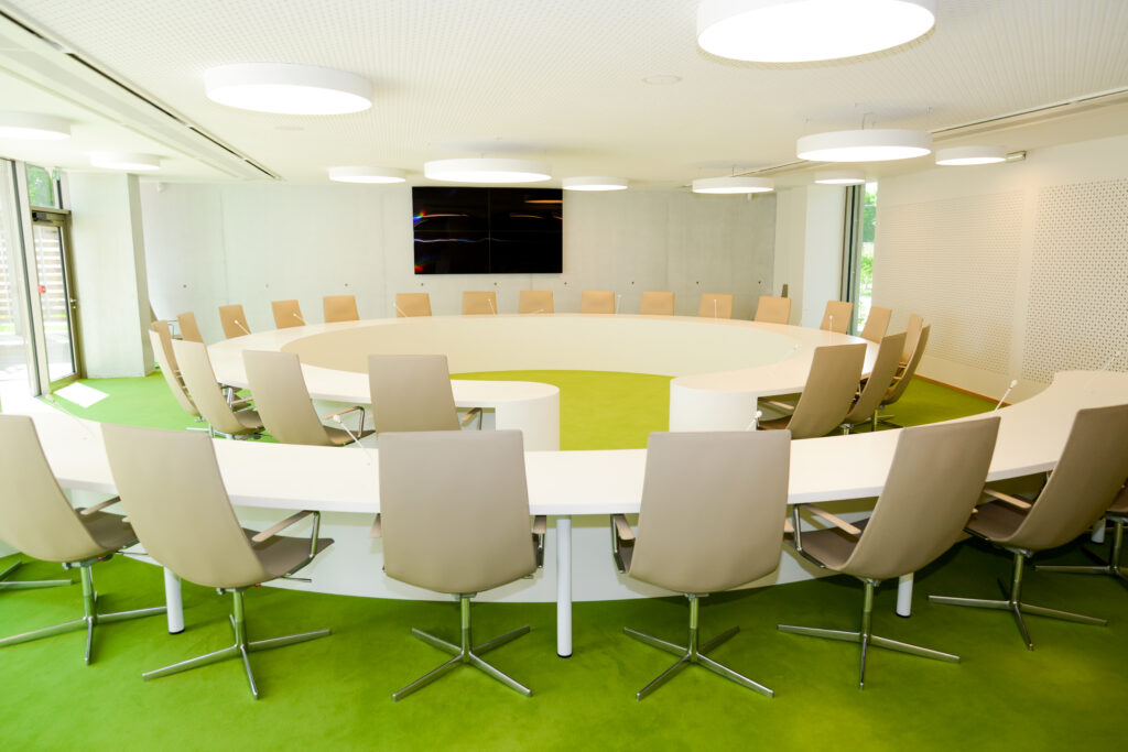 Ensemble de mobilier composé d’un bureau blanc en demi-cercle avec chaise, associé à une table ronde avec assise assortie