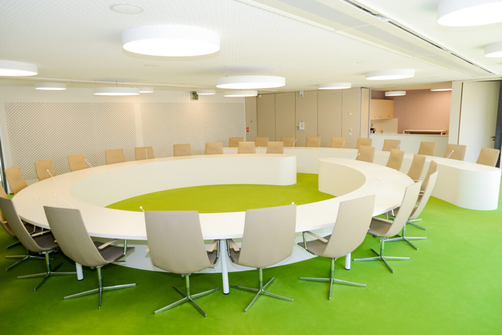 Table ronde entourée de chaises design, posée sur un sol vert