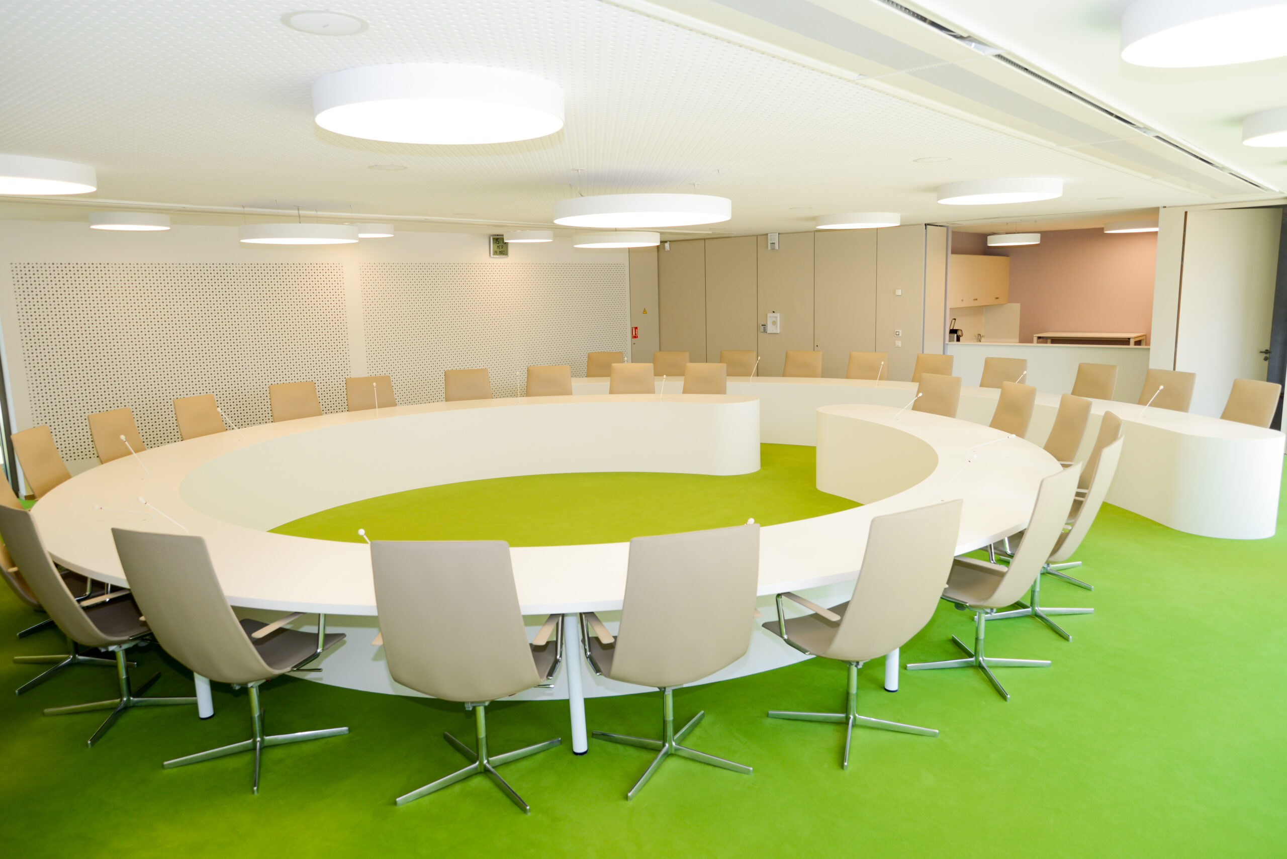 Table ronde entourée de chaises design, posée sur un sol vert