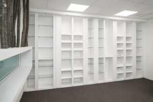 Grand meuble et Bibliothèque sur mesure de rangement blanc intégrant de nombreuses étagères et niches ouvertes, conçu sur mesure pour optimiser l’espace