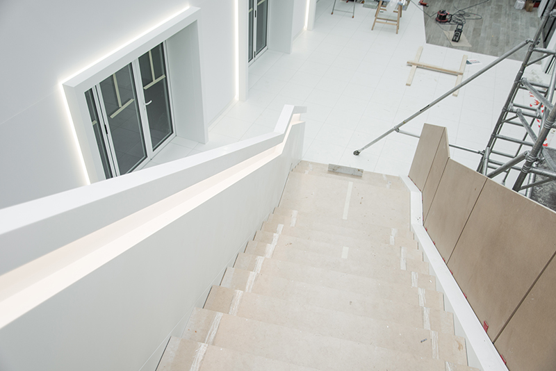 Vue plongeante depuis le haut d’un escalier en bois, avec une porte visible sur la gauche
