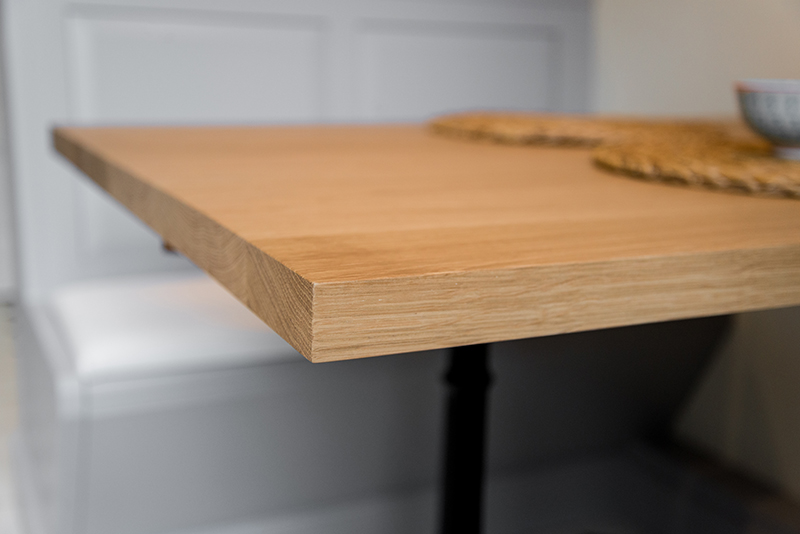 Gros plan sur une table en bois naturel avec veinures apparentes, mettant en valeur la texture du matériau et le design artisanal.