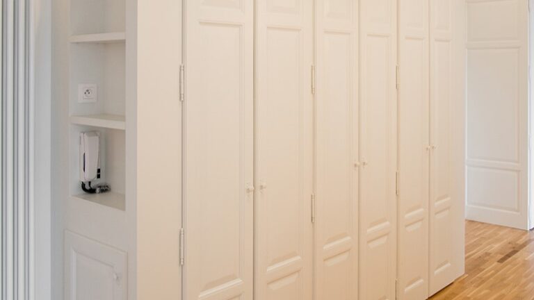 Armoire blanche à six portes avec meuble et étager à gauche, intégrée dans un projet d’aménagement intérieur sur mesure réalisé par L’Arche du Bois, entreprise de menuiserie et d’agencement intérieur en Alsace et en France.