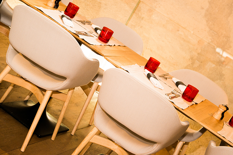 Tables de salle à manger dressées avec des verres, couverts et couteaux, accompagnées de chaises assorties