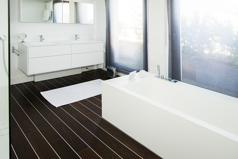 Salle de bain sur mesure par LDC Agencement – L’Arche du Bois : baignoire centrale, meuble vasque double à gauche avec miroir en dessous, design contemporain et agencement personnalisé.