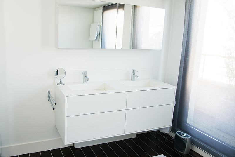 Salle de bain sur mesure par LDC Agencement – L’Arche du Bois : meuble vasque double avec deux robinets et miroir, porte vitrée à droite, design contemporain et agencement personnalisé.