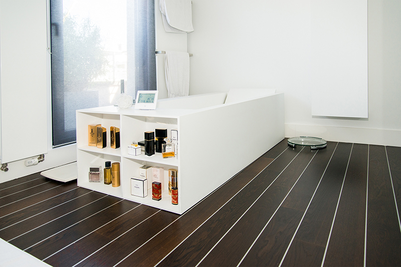 Salle de bain sur mesure par LDC Agencement – L’Arche du Bois : baignoire centrale avec rangements intégrés en dessous, design contemporain et agencement personnalisé.