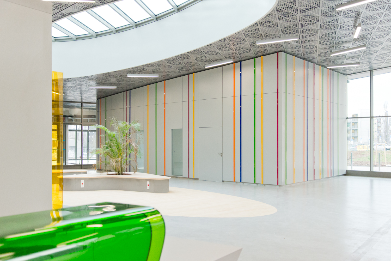 Vue extérieure d’un module aux murs blancs décorés de lignes colorées, avec une plante positionnée en face — un agencement contemporain et harmonieux conçu par Arche du Bois, alliant design graphique et touche naturelle.