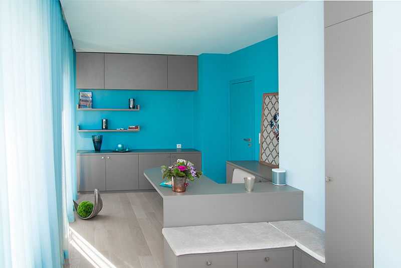 Vue intérieure avec une armoire à droite suivie d'une porte, un rideau à gauche, et plusieurs placards de rangement en face.