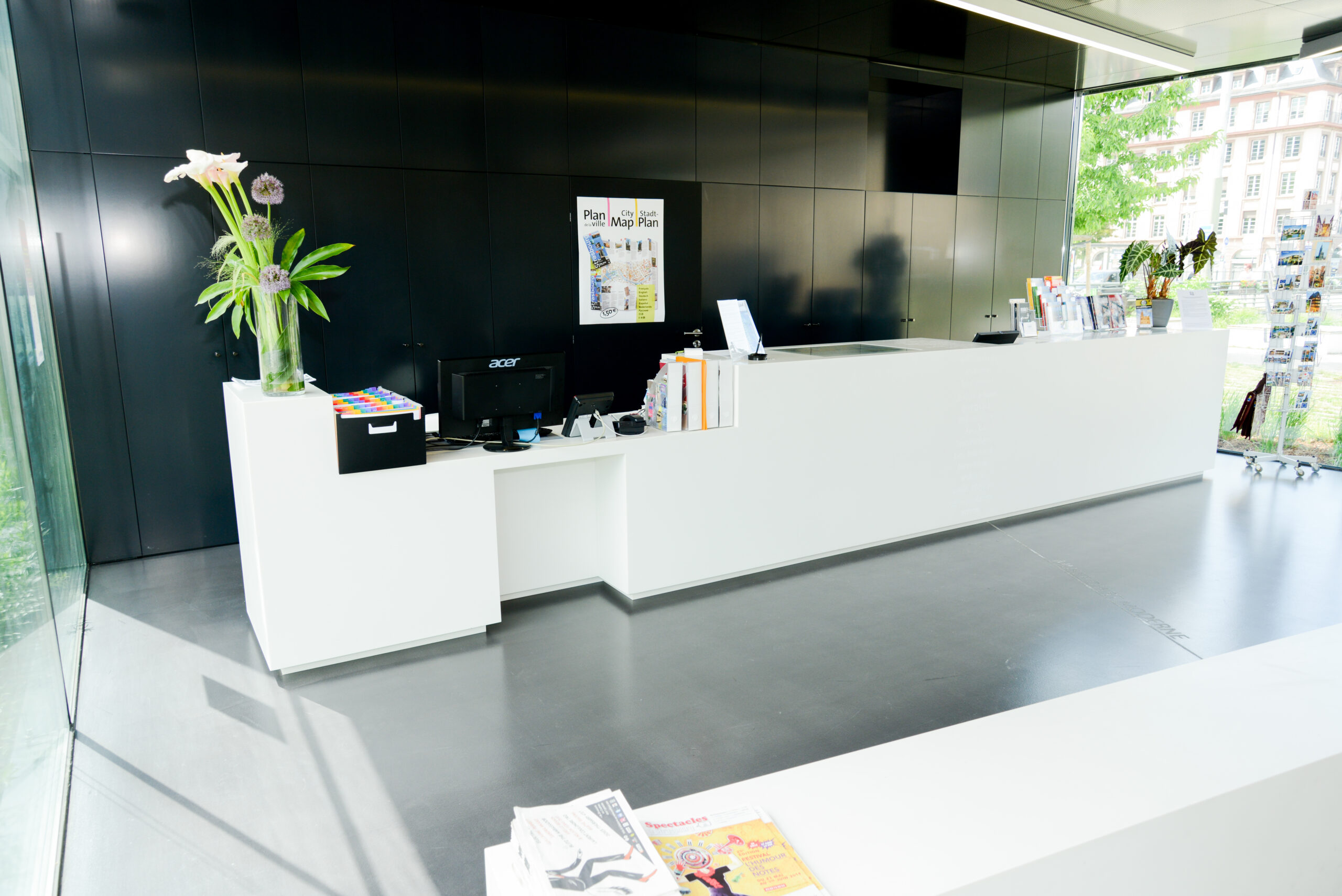 Accueil blanc au centre de l’image, encadré de deux grands vases décoratifs de chaque côté, avec une armoire noire positionnée à l’arrière-plan