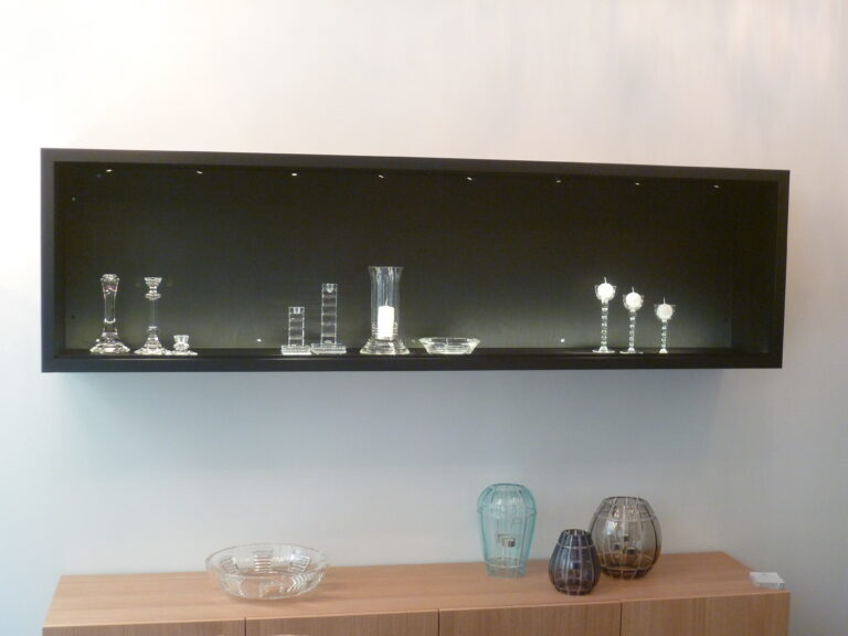 Niche d’exposition noire mettant en valeur un bougeoir décoratif — un agencement sobre et raffiné réalisé par Arche du Bois pour souligner l’élégance des objets d’art et de décoration.