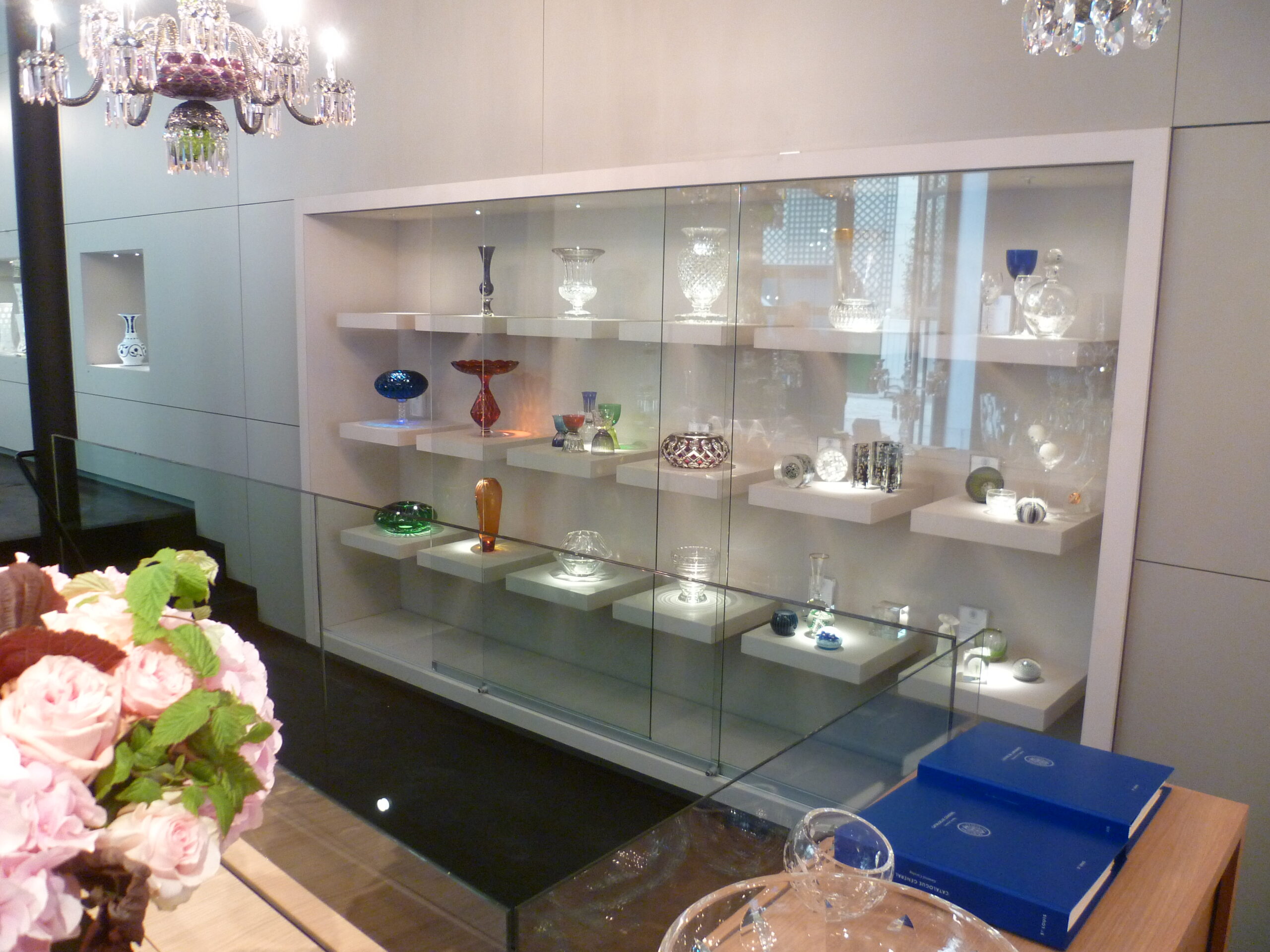 Vitrine d’exposition conçue par Arche du Bois, présentant des objets décoratifs en verre disposés avec soin — un agencement raffiné et lumineux mettant en valeur la transparence et la délicatesse des éléments décoratifs.