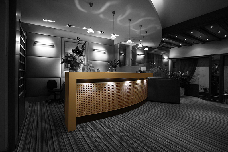 Comptoir arrondi de couleur marron, avec un éclairage intégré au-dessus et en dessous, conçu par Arche du Bois pour créer une atmosphère chaleureuse et accueillante dans l’espace d’accueil.