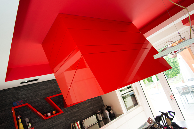Plafond de cuisine de couleur rouge avec une hotte intégrée, apportant une touche moderne et design à l’espace culinaire