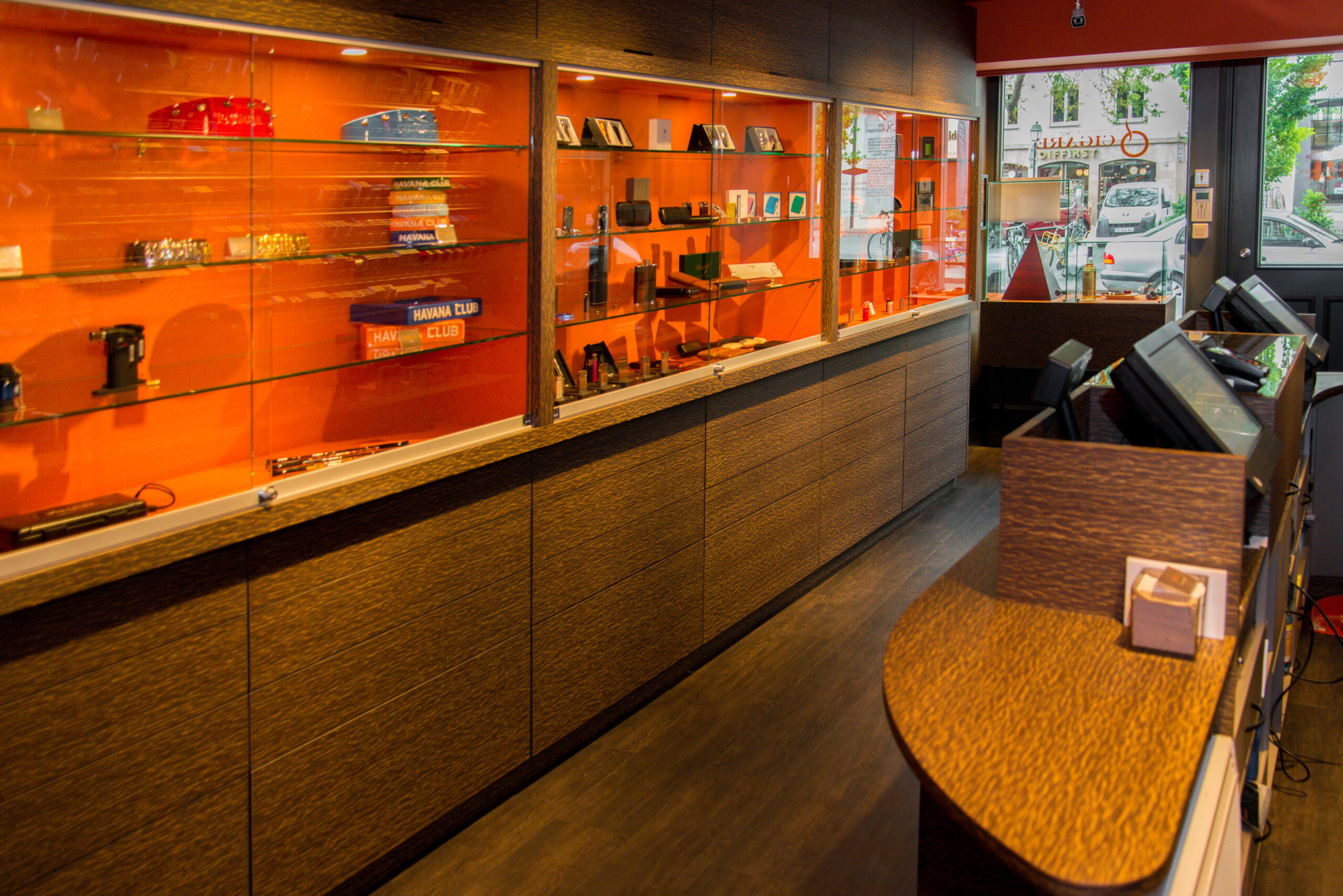 Étagères à portes vitrées avec un fond orange vif, surmontant des compartiments inférieurs en bois naturel — un agencement original et structuré conçu par Arche du Bois, alliant design coloré et fonctionnalité.