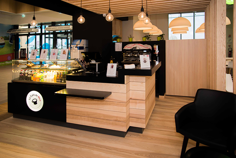 Vue du comptoir café de Pizza de Nico avec un habillage en bois naturel aux teintes chaudes — un agencement élégant et convivial qui reflète l’ambiance chaleureuse de l’enseigne et renforce son identité visuelle.