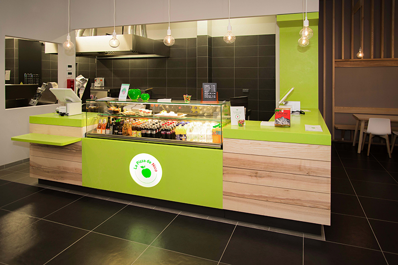 Comptoir d’accueil de l’enseigne Pizza de Nico, aménagé dans les tons caractéristiques de la marque — un agencement moderne et dynamique mettant en valeur l’identité visuelle de l’enseigne dans un cadre convivial.