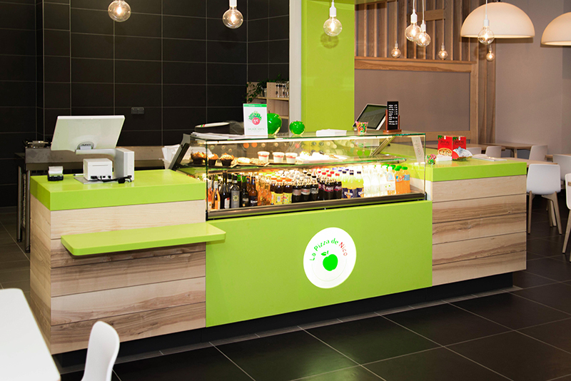 Comptoir d’accueil de l’enseigne Pizza de Nico, aménagé dans les tons caractéristiques de la marque — un agencement moderne et dynamique mettant en valeur l’identité visuelle de l’enseigne dans un cadre convivial.