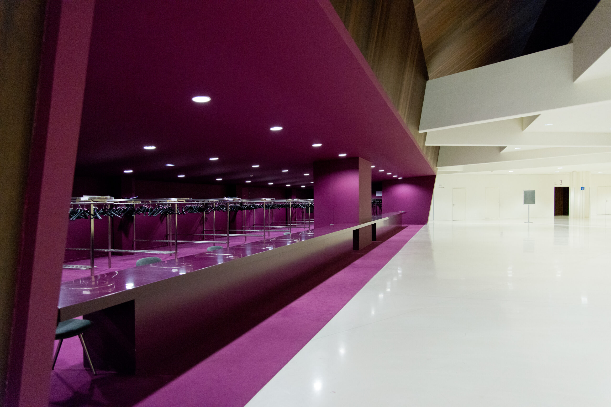 Salle avec un mur blanc sur la droite et un comptoir d’accueil violet sur la gauche