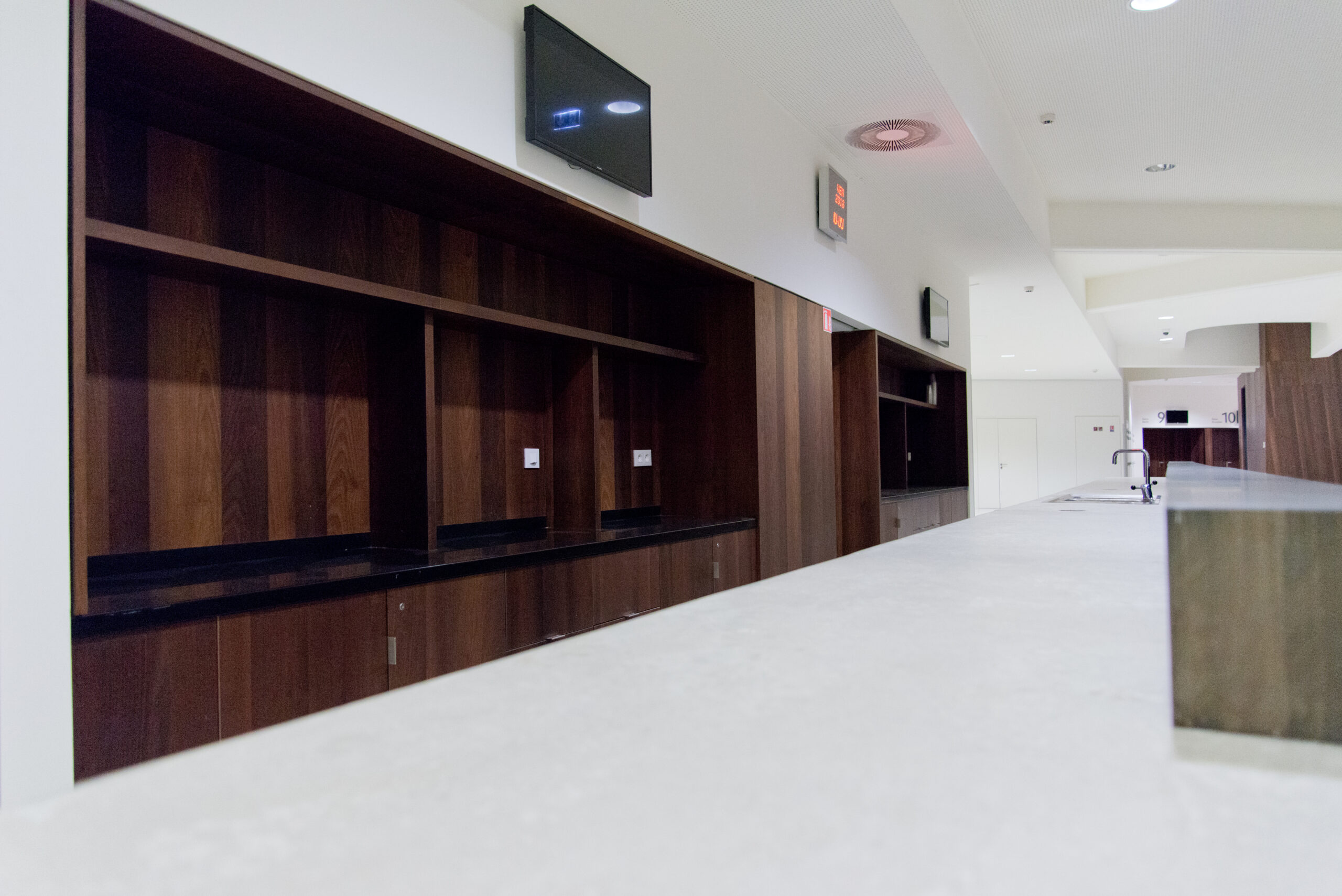 Grand meuble et étagère en bois intégrés dans un mur blanc, avec une télévision fixée au-dessus