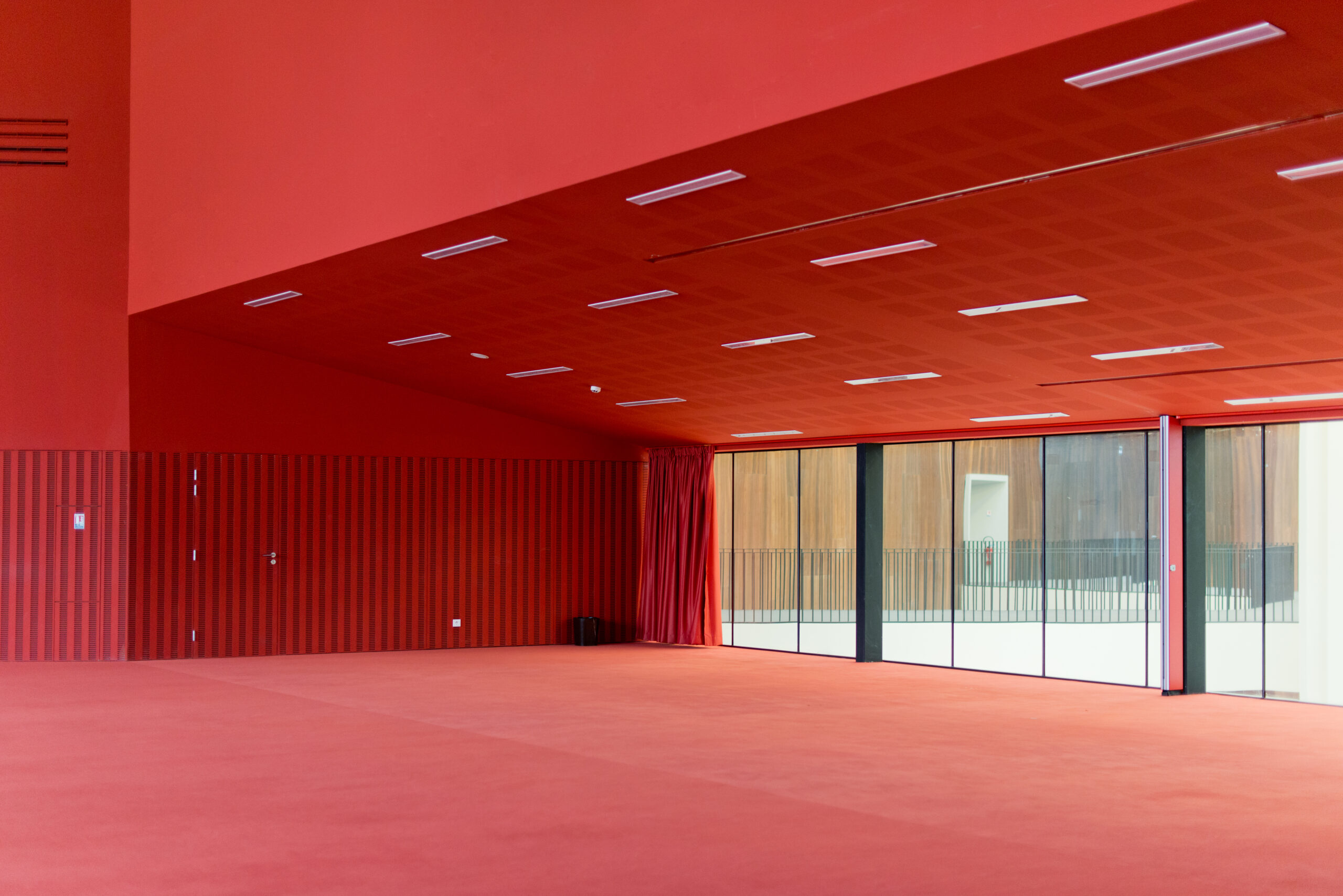 Entrée marquée par des murs et un plafond rouges, avec des portes vitrées apportant transparence et luminosité