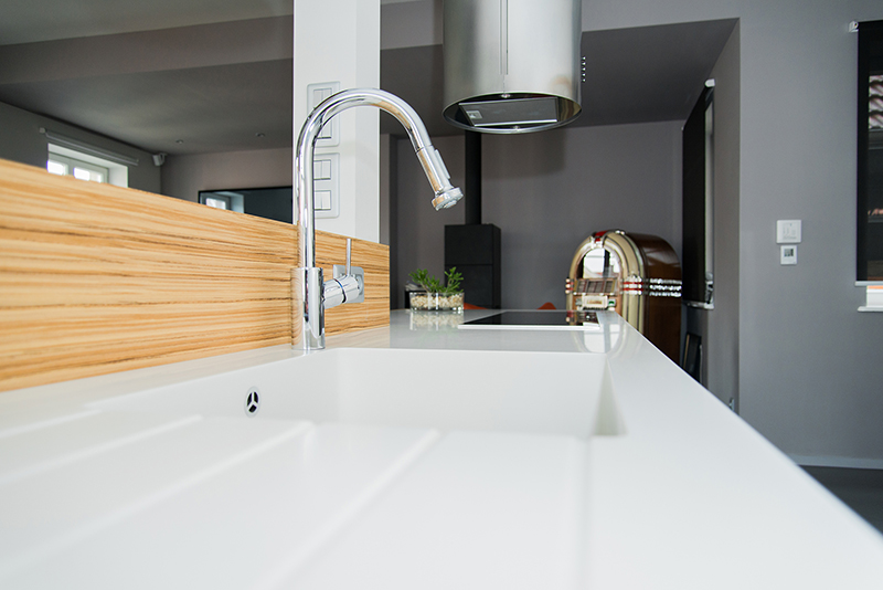 Cuisine sur mesure par LDC Agencement – L’Arche du Bois : lavabo blanc avec robinet moderne et hotte en arrière-plan.