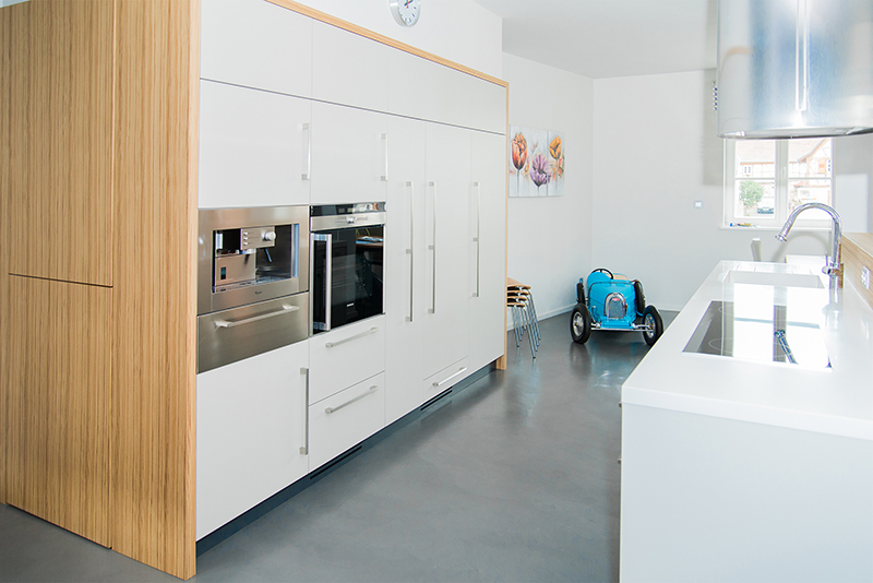 Cuisine sur mesure par LDC Agencement – L’Arche du Bois : lavabo avec robinet à droite, placards à gauche avec micro-ondes et four intégrés.