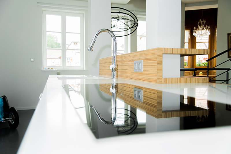Cuisine sur mesure par LDC Agencement – L’Arche du Bois : robinet central avec plaque de cuisson devant, fenêtres en arrière-plan et deux colonnes de rangement.