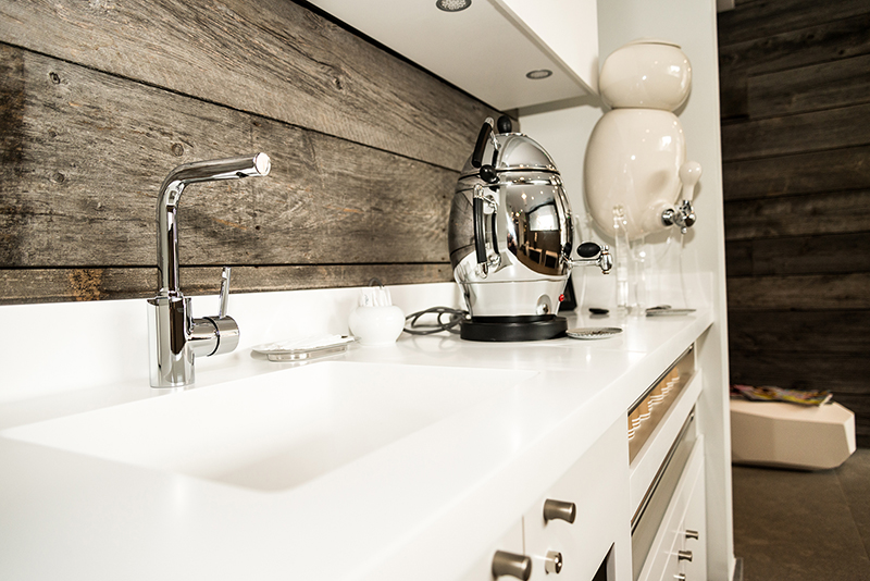 Évier blanc installé sur un plan de travail, avec un samovar posé à côté — un agencement fonctionnel et convivial signé Arche du Bois, mêlant modernité