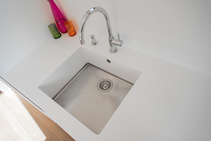 Vue plongeante sur un évier de cuisine encastré, intégré dans un plan de travail, avec robinetterie moderne.