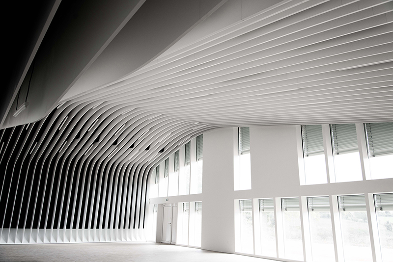 Plafond courbe avec un design rayé distinctif, complété par de grandes fenêtres vitrées intégrées au mur