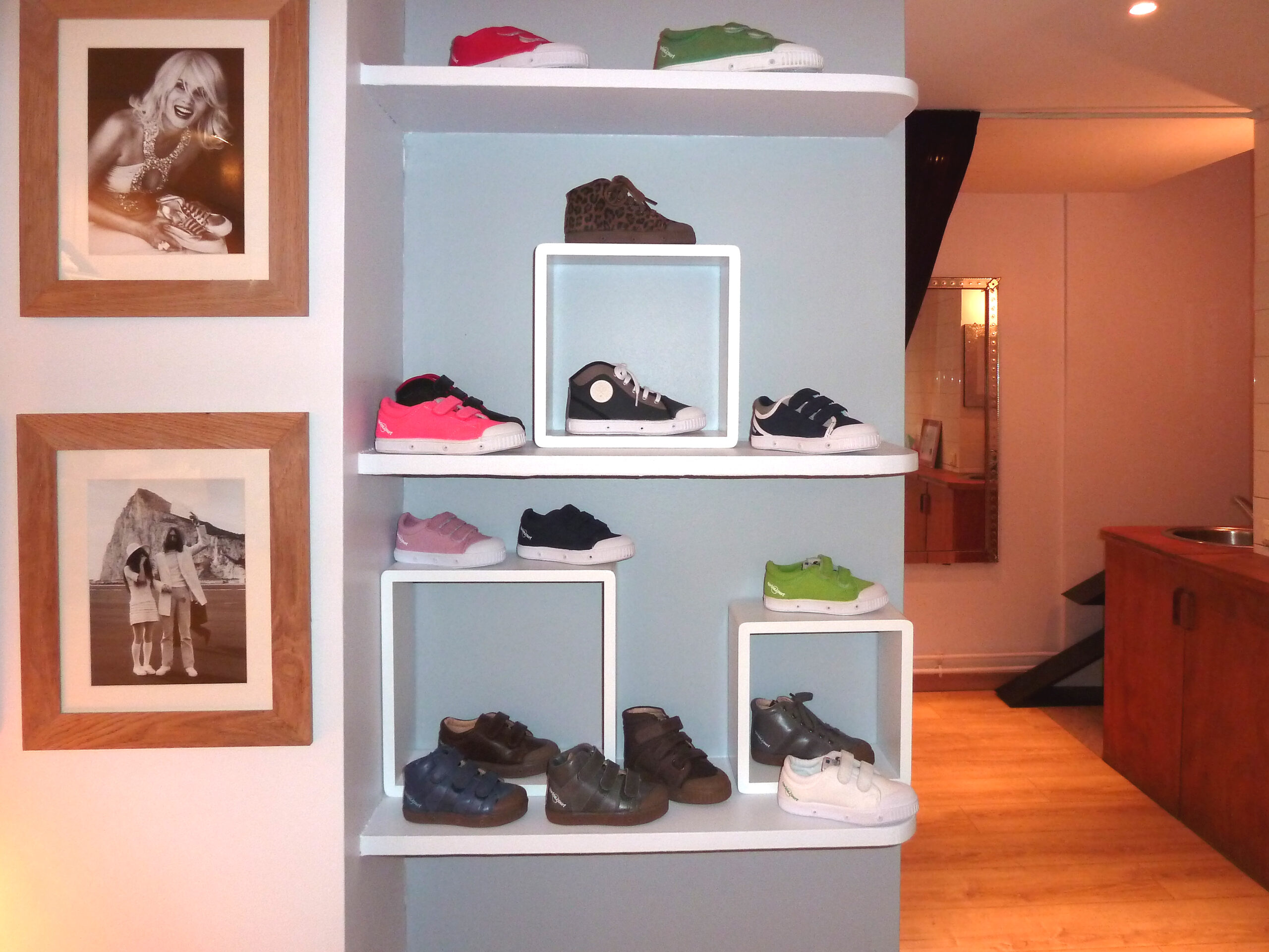 Étagère murale avec des chaussures exposées, accompagnée de deux cadres photo décoratifs posés à côté — un agencement alliant fonctionnalité et touches personnelles, signé Arche du Bois.