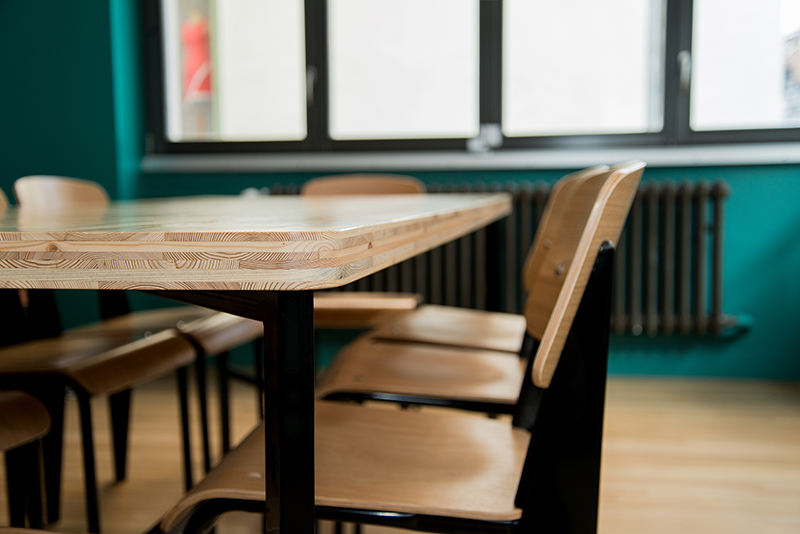 Vue rapprochée d’une table et d’une chaise positionnées devant une fenêtre, laissant entrer la lumière naturelle