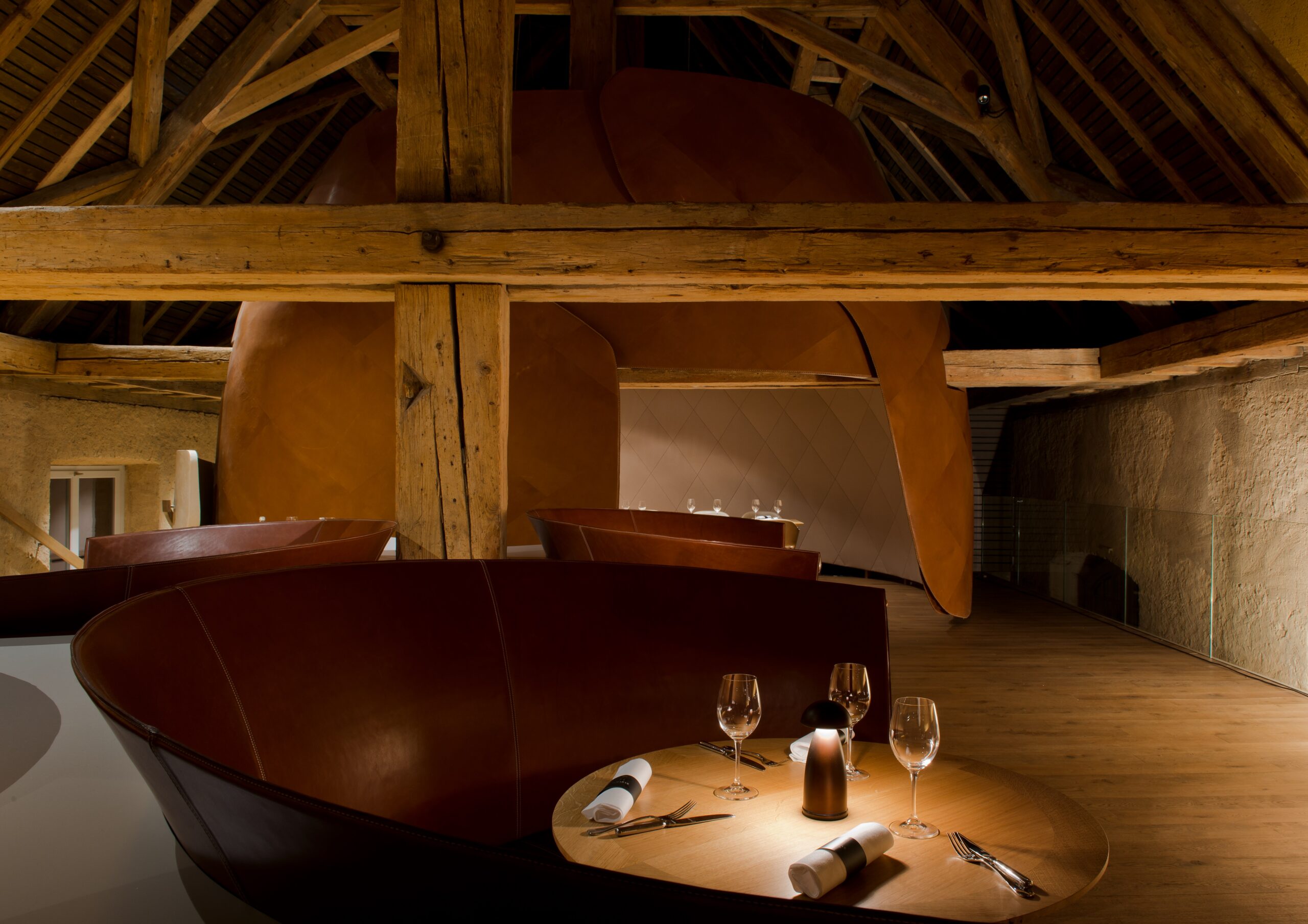 Ensemble table et chaises de salle à manger au premier plan, avec en arrière-plan des poutres et colonnes en bois massif