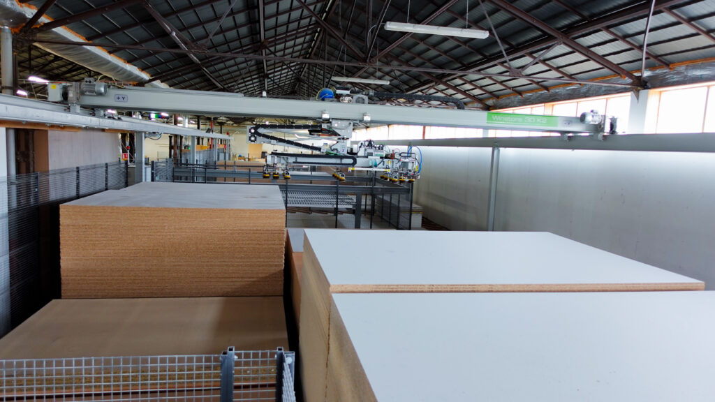 Robot WinStore 3D K2 manipulant des panneaux mélaminés et stratifiés dans l’atelier de L’Arche du Bois, assurant une manutention automatisée et silencieuse des matériaux.